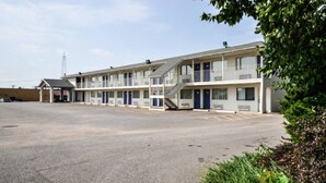 Een motel met een centrale parkeerplaats en meerdere kamers met balkons.