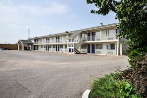 A motel with a central parking area and multiple rooms with balconies. - 1 King Bed | ADA/RI Shower (Saint Joseph)