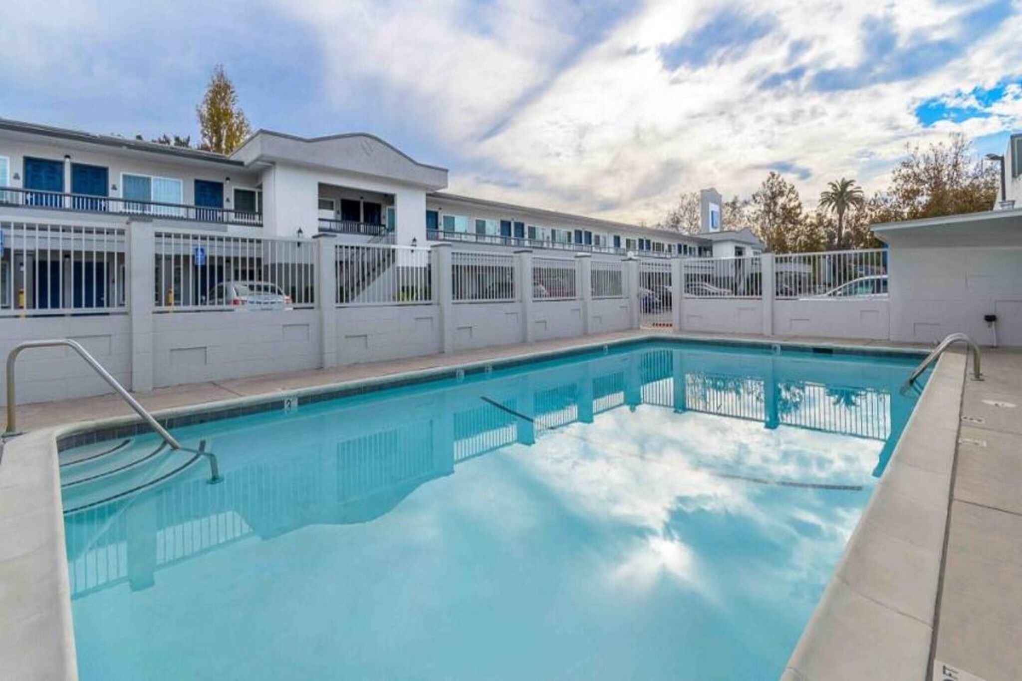 A swimming pool with a white fence and a building in the background.