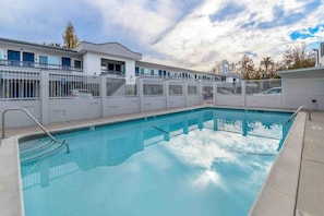 Una piscina con cerca blanca y un edificio al fondo.