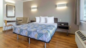 Una habitación de hotel con cama, escritorio, silla y calefactor.