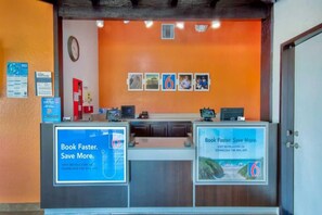 A reception desk with two computer monitors, a clock, and framed pictures on the wall.