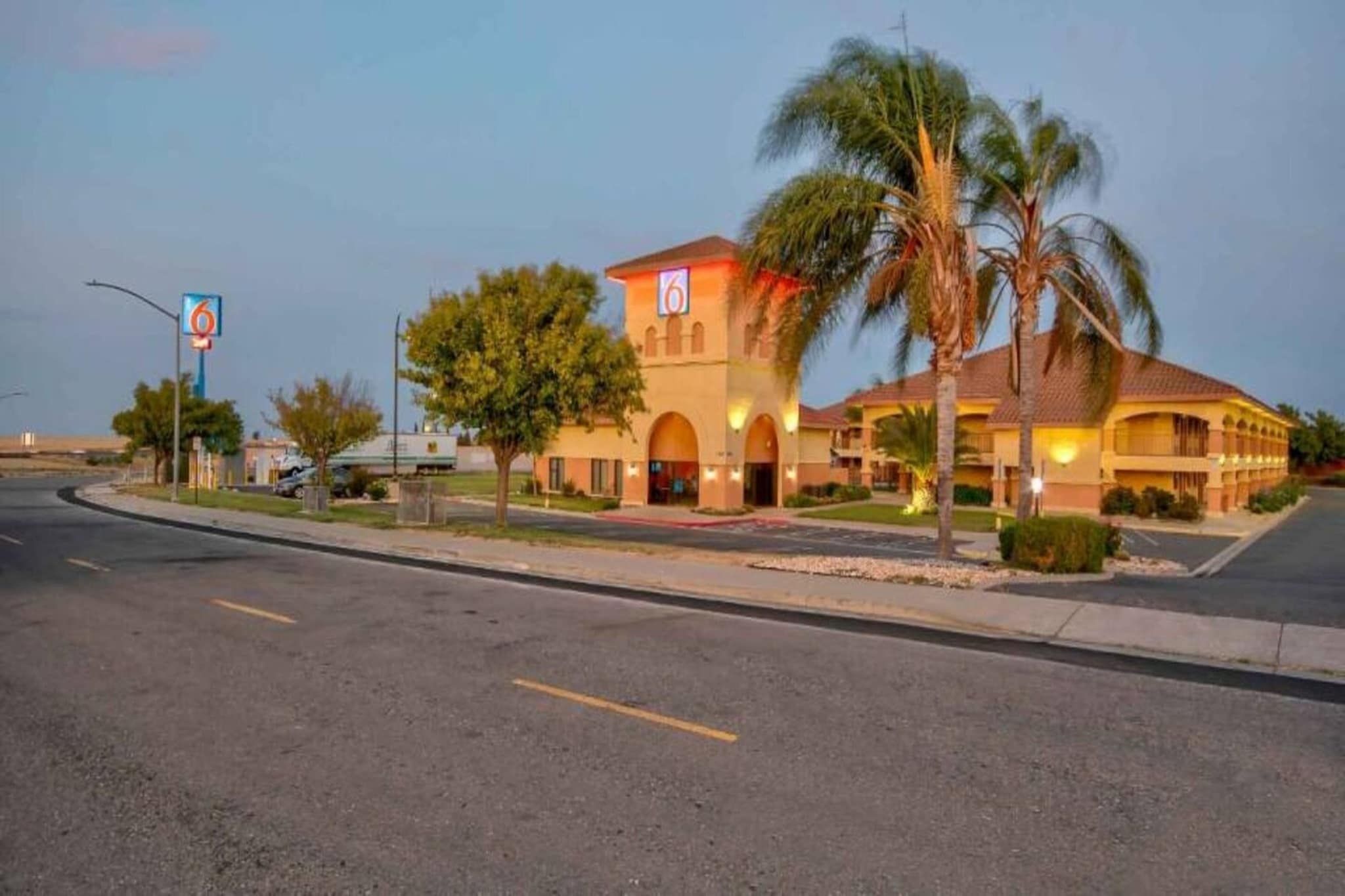 A hotel with a large arched entrance, palm trees, and a clear sky.