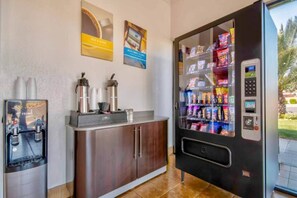 A vending machine with snacks and a coffee machine with cups and a bottle.