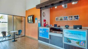 A reception area with a counter, chairs, a clock, and framed pictures on the wall. - 1 Queen|Mobility|Tub|Nsmk (Santa Nella)
