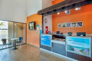 A reception area with a counter, chairs, a clock, and framed pictures on the wall. - 1 Queen|Mobility|Tub|Nsmk (Santa Nella)