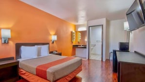 A hotel room with a bed, bedside tables, a desk, a television, and a bathroom door. - 1 Queen|Mobility|Tub|Nsmk (Santa Nella)