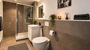 A modern bathroom with a glass-enclosed shower, a toilet, and a sink.