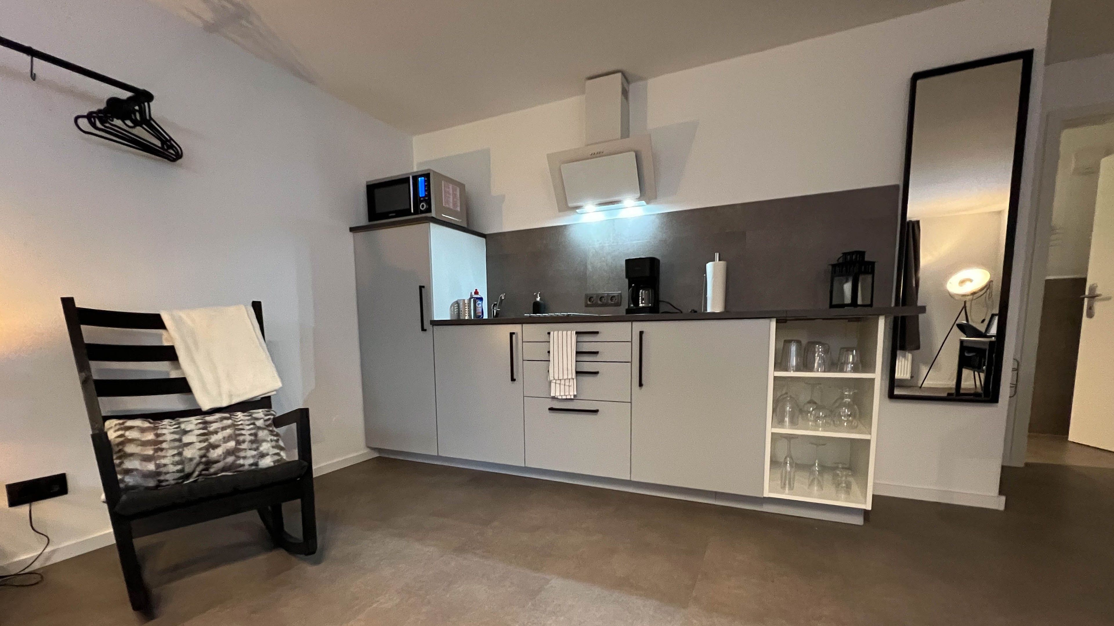 A compact kitchenette with a microwave, coffee maker, and glassware storage.