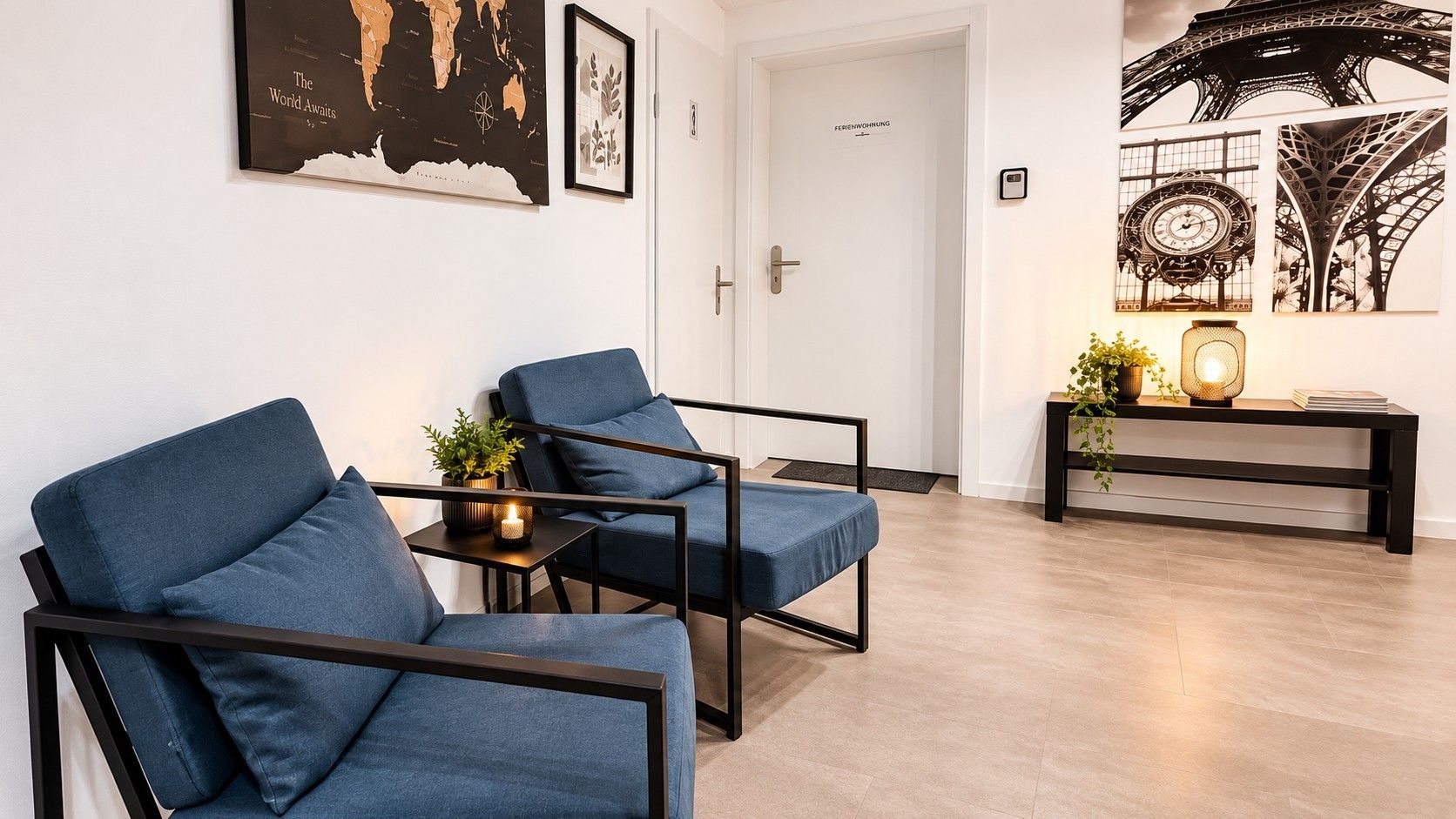 Ein modernes Wohnzimmer mit zwei blauen Sesseln, einem kleinen Tisch mit Pflanze und einer Konsolentisch mit Dekorationselementen.