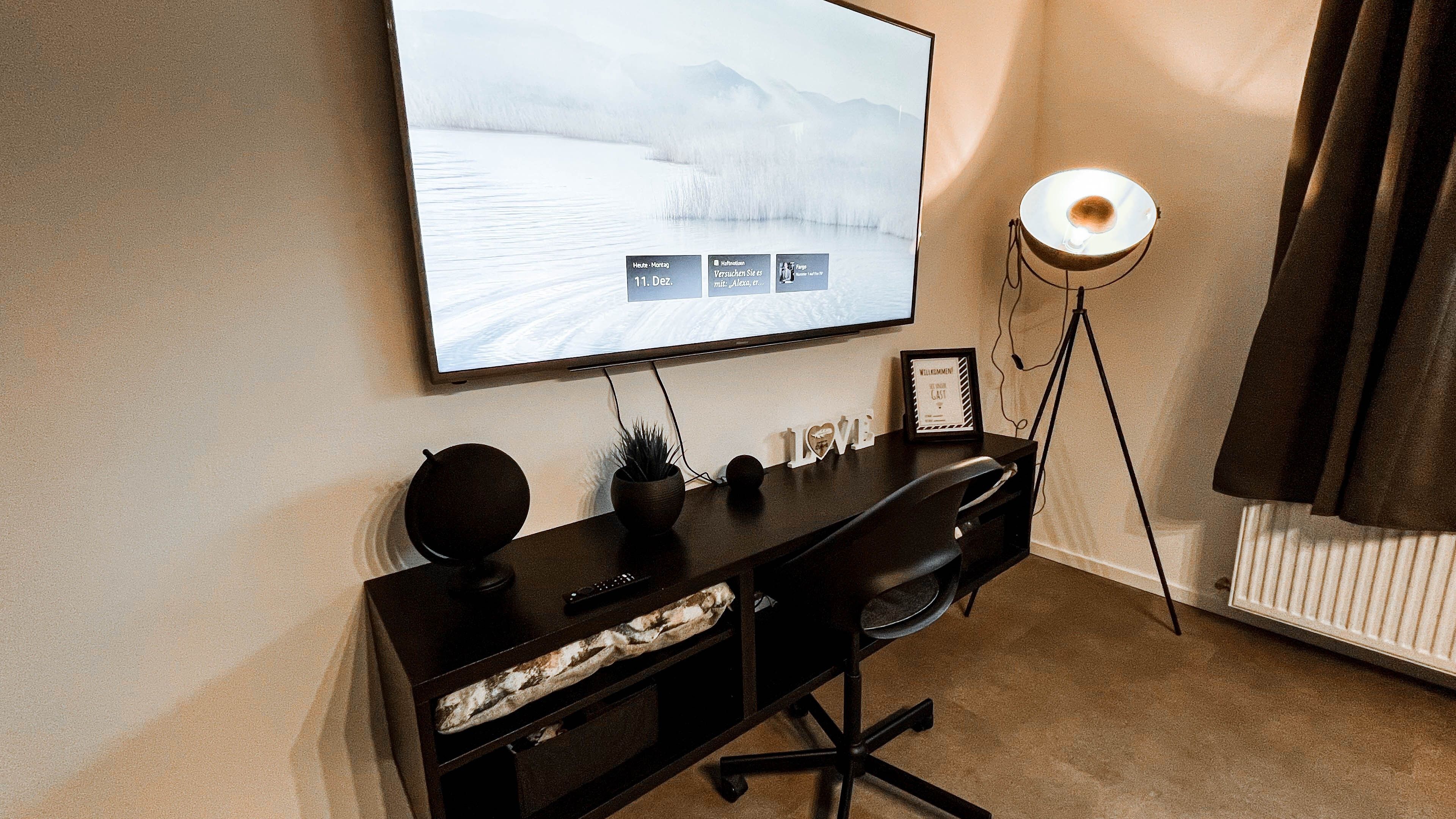 Ein moderner Schreibtisch mit Computerbildschirm, Schreibtischlampe und Dekorationselementen.