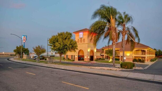 A hotel with a large arched entrance, palm trees, and a clear sky. - 2 Queen Beds | Non-Smoking (Santa Nella)