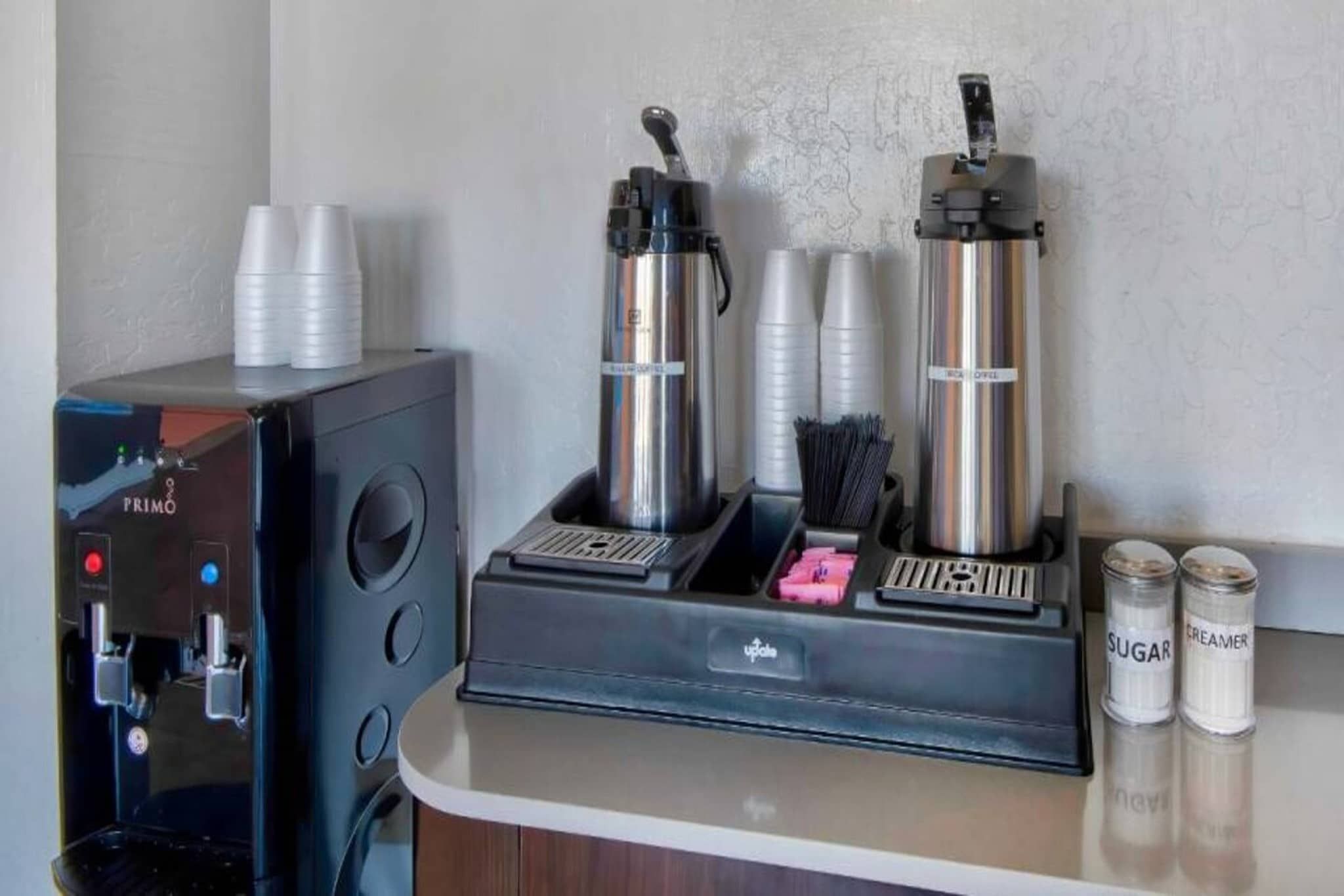Un espace dédié au café, équipé d’une machine à café, de tasses et de distributeurs de condiments.