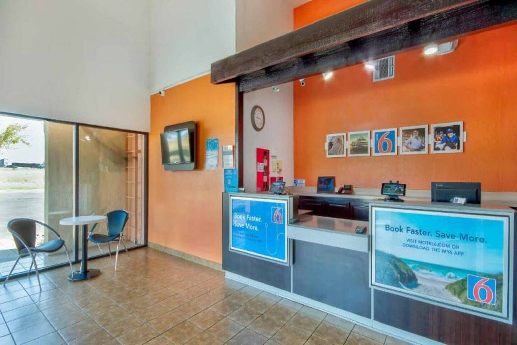 A reception desk with a clock, informational posters, and a window to the left.
