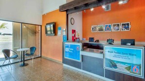 A reception desk with a clock, informational posters, and a window to the left. - 2 Queen Beds | Non-Smoking (Santa Nella)