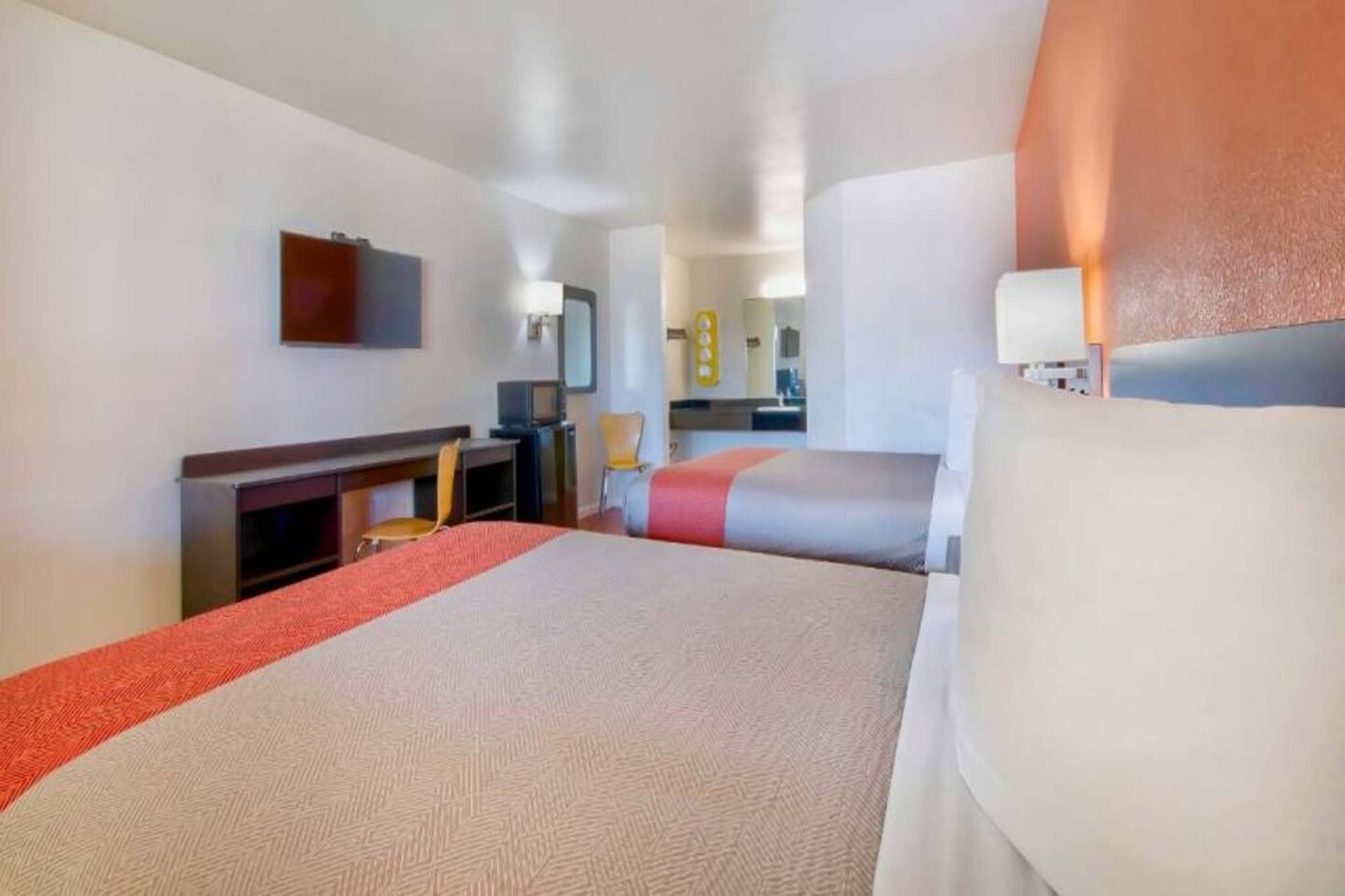 A hotel room with a bed, a desk, a chair, and a television.