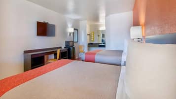 A hotel room with a bed, a desk, a chair, and a television.