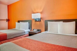 A hotel room with two beds, a nightstand, and a wall-mounted light fixture.