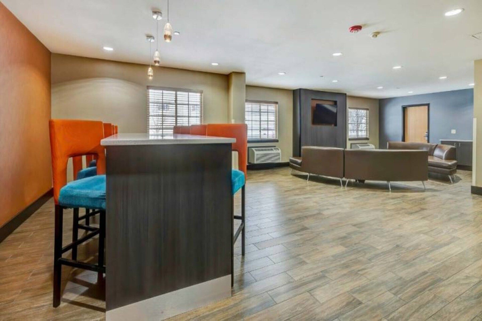 A modern hotel lobby with a bar area, seating, and a large window.