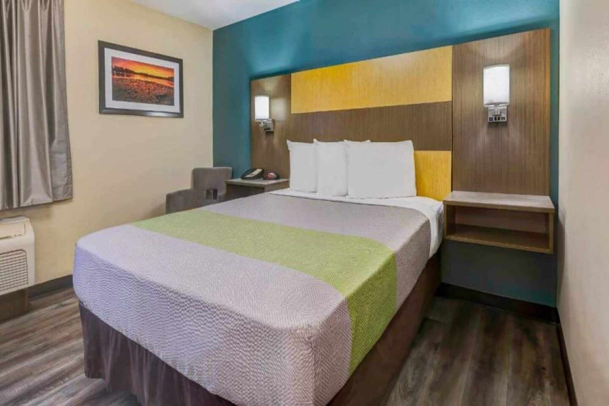 A hotel room with a bed, bedside tables, a desk, and a chair.