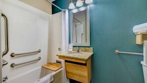 Une salle de bain avec une douche, un lavabo avec un miroir et un porte-serviettes.