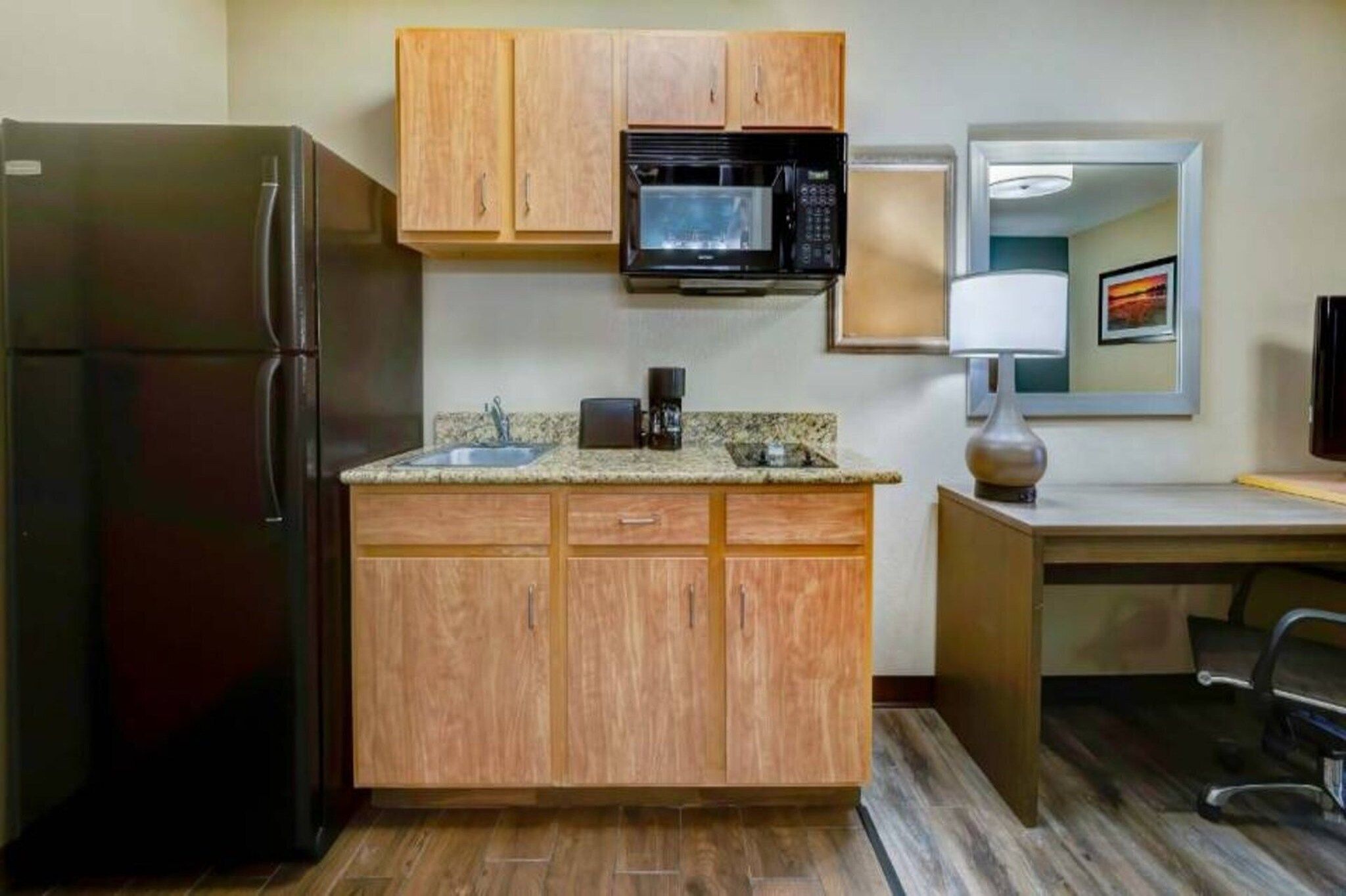 A compact kitchen with a refrigerator, microwave, and a coffee maker on the countertop.