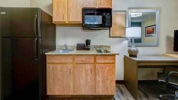 A compact kitchen with a refrigerator, microwave, and a coffee maker on the countertop.