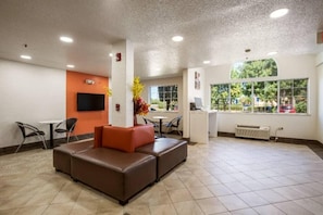 A lobby with a seating area, a TV mounted on the wall, and a window with a view of the outdoors.