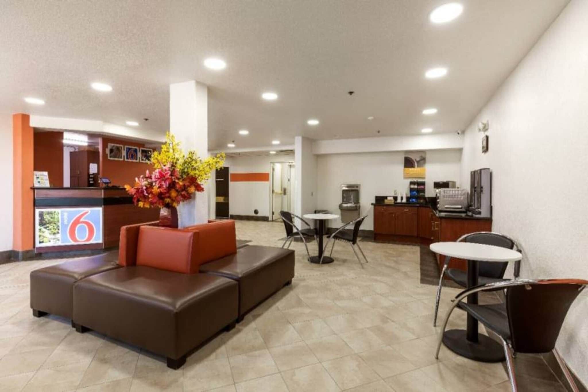 Um saguão de hotel com balcão de recepção, área de estar e cozinha compacta.