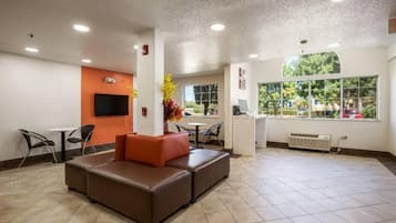 A lobby with a seating area, a TV mounted on the wall, and a window with a view of the outdoors.