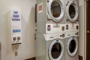 A laundry area with stacked washing machines and a soap dispenser.