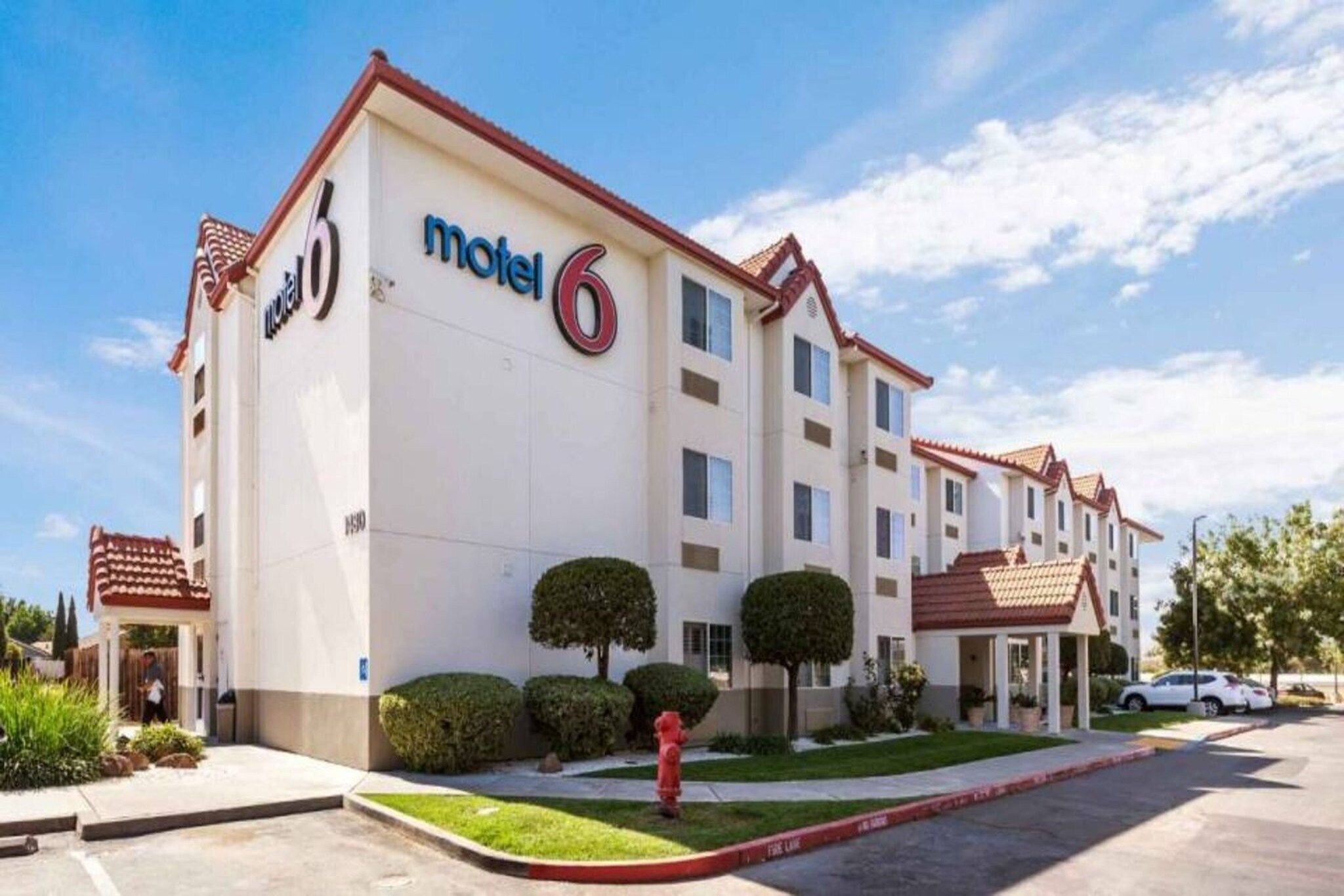 Un motel reconnaissable à son grand panneau « Motel 6 », à ses nombreuses fenêtres et à son parking.