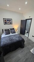 Un dormitorio con cama, mesita de noche y espejo.