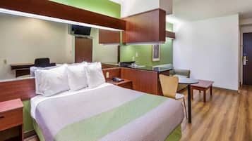 A hotel room with a bed, a desk, a chair, a small table, and a mirror.