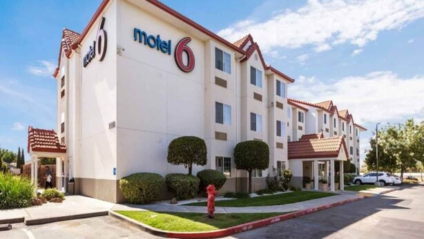 A motel with a prominent 'motel 6' sign, multiple windows, and a red fire hydrant in the front yard. - Queen Bed|Mobility|Suite|Nsmk|Sofa-bed (Dixon)