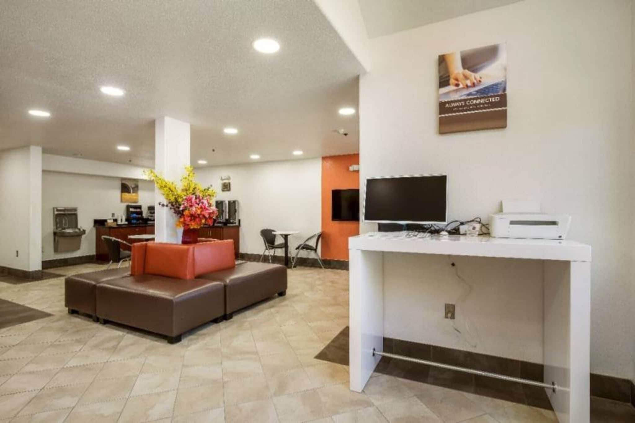A reception area with a sofa, a desk with a computer, a TV, and a poster on the wall.