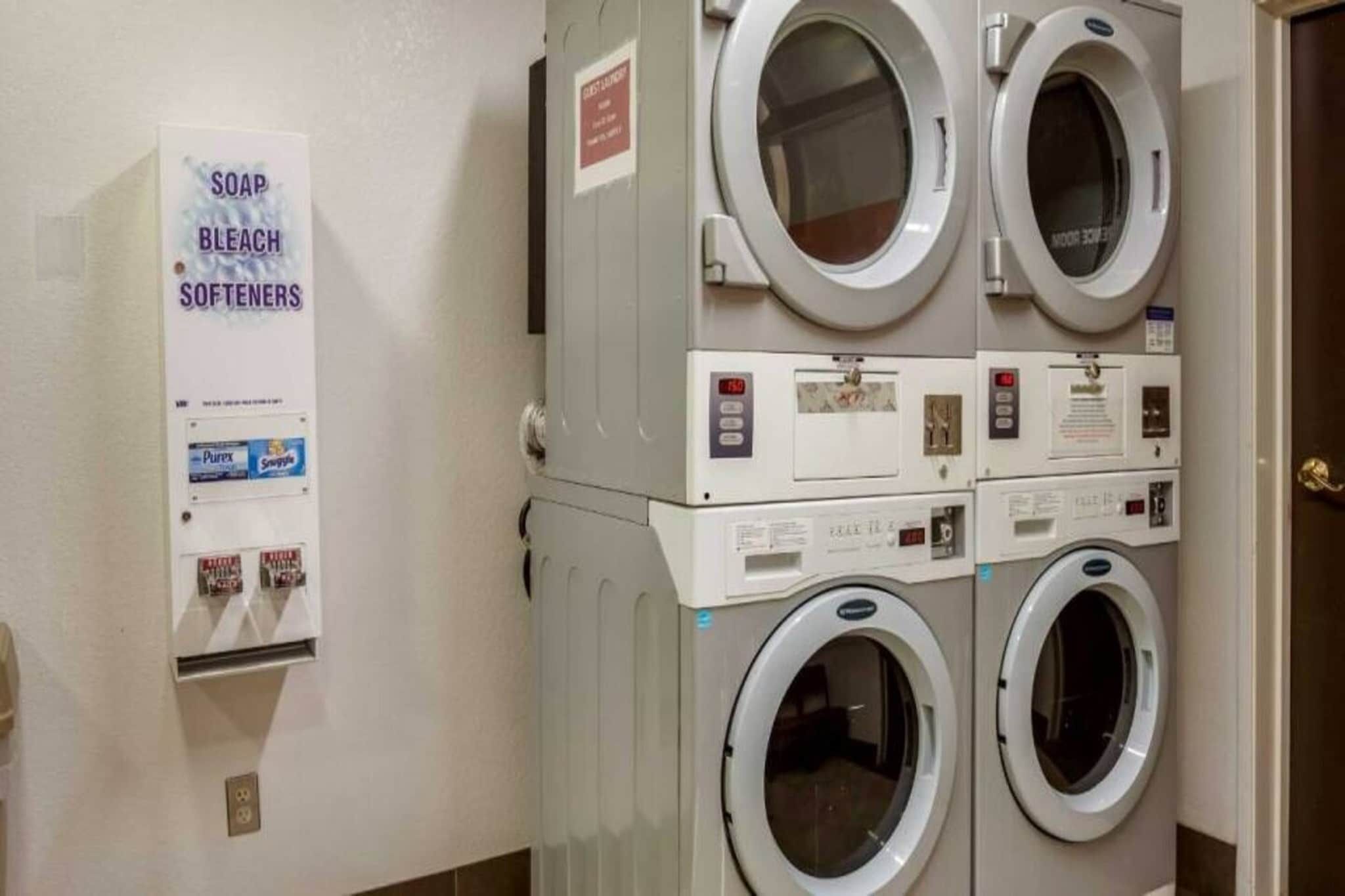 A laundry area with stacked washing machines and a soap dispenser.