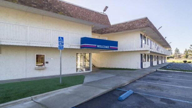 A hotel with a 'Welcome' sign, a disabled parking sign, and a parking lot. - 1 Full Bed | Smoking | Oroville (Oroville)