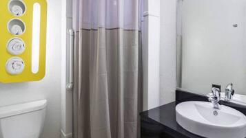 A bathroom with a toilet, a shower curtain, a sink, and a mirror.