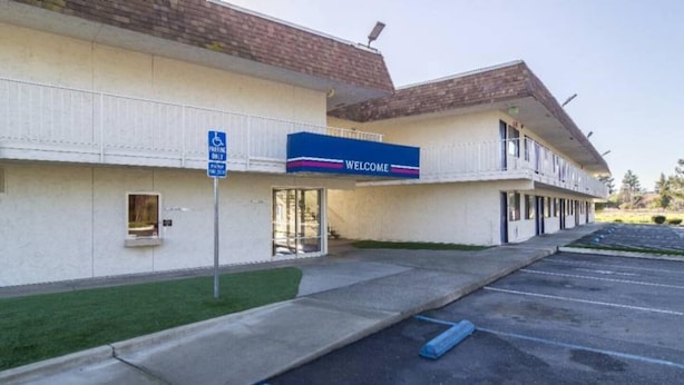 A hotel with a 'Welcome' sign, a disabled parking sign, and a parking lot. - 2 Full Beds | Non-smoking (Oroville)