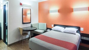Een hotelkamer met een bed, een bureau, een stoel en een spiegel.