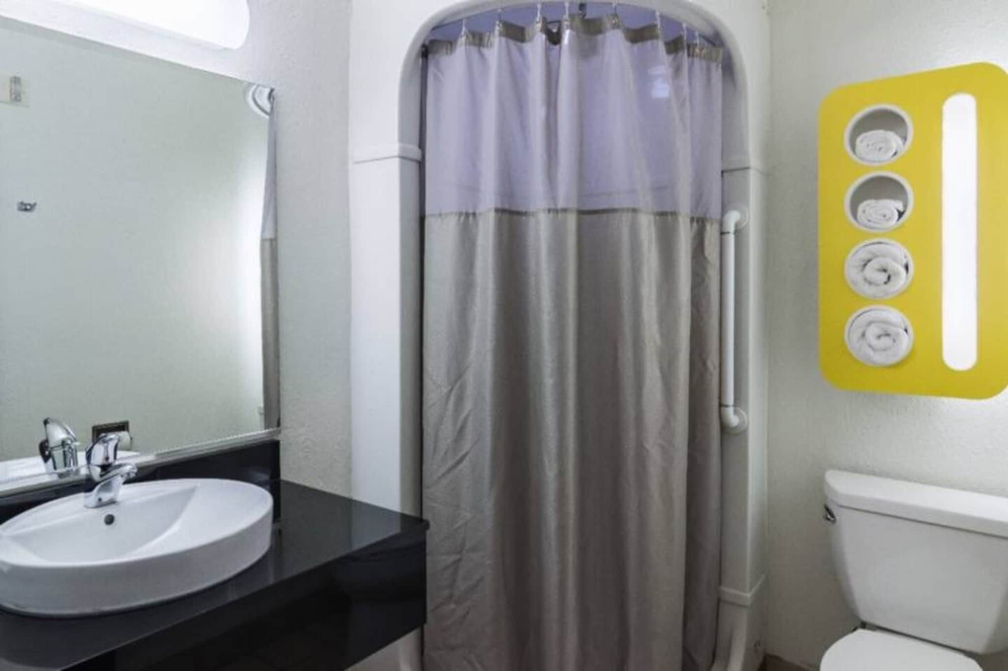 A bathroom with a sink, mirror, toilet, and shower curtain.