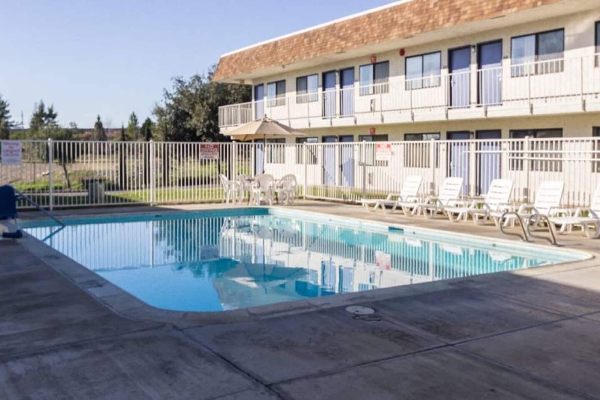 A swimming pool with lounge chairs and a building with multiple windows in the background.