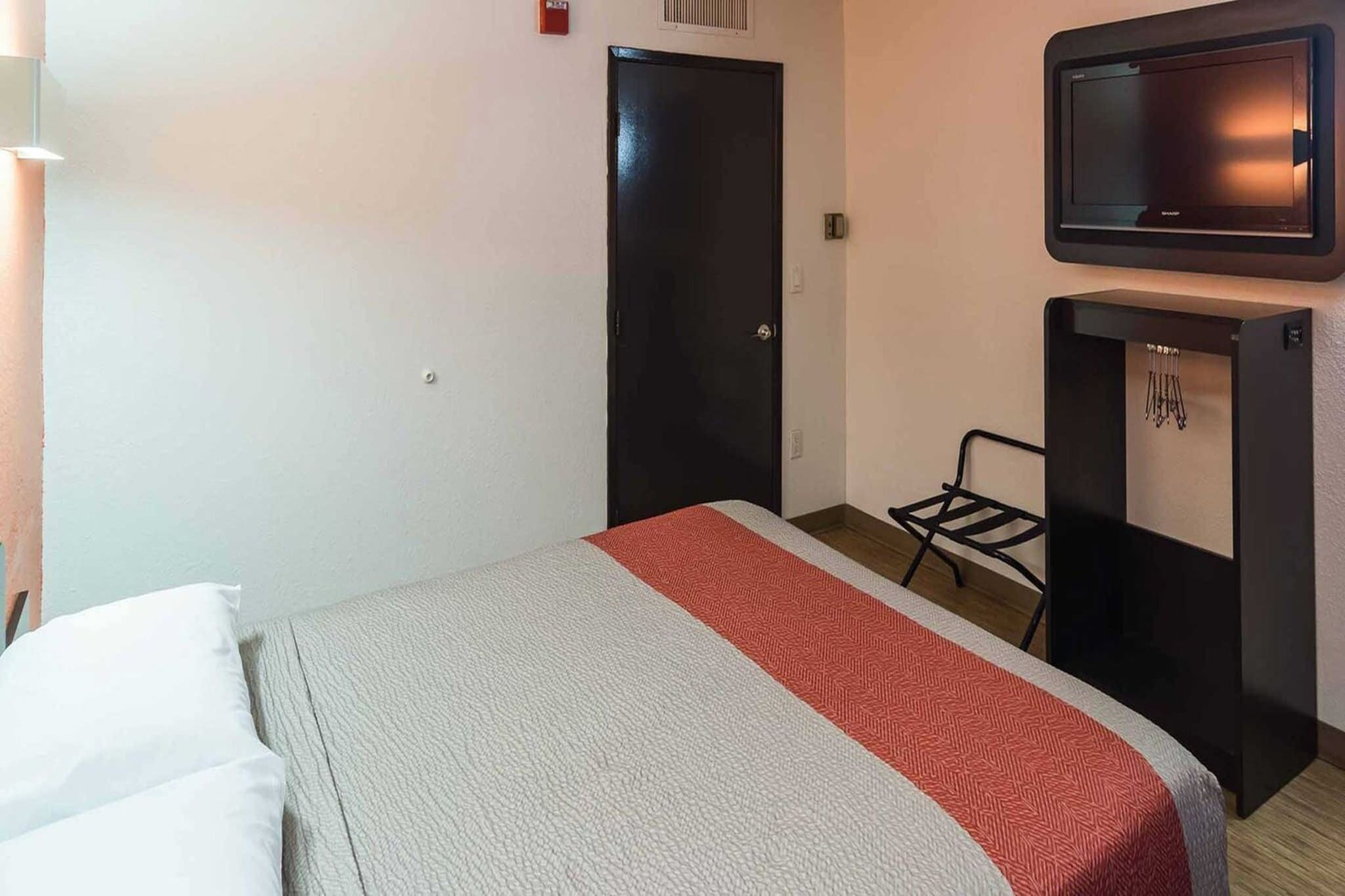 Habitación de hotel con cama, televisión, escritorio y silla.