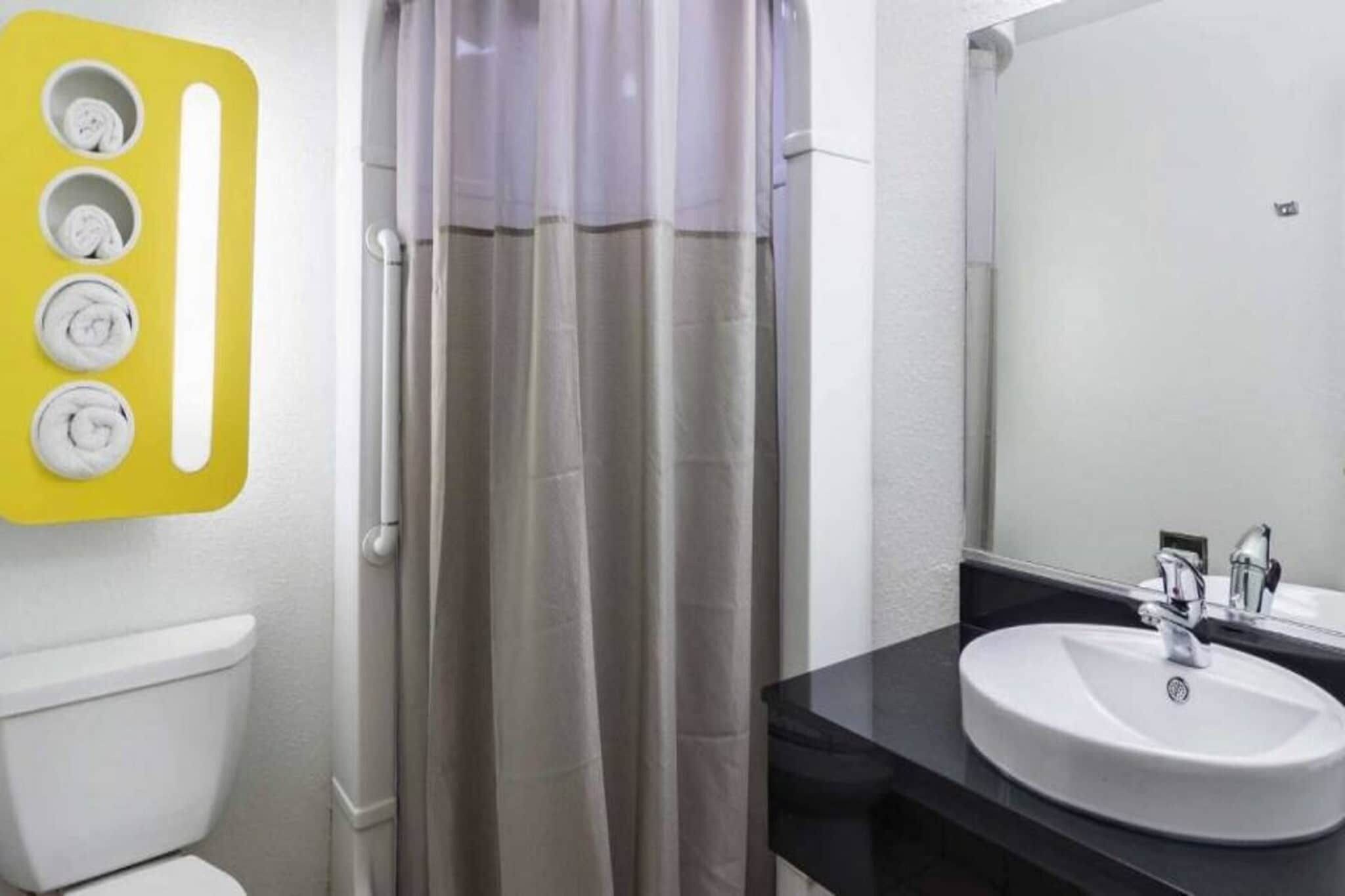 A bathroom with a toilet, a shower curtain, a sink, and a mirror.