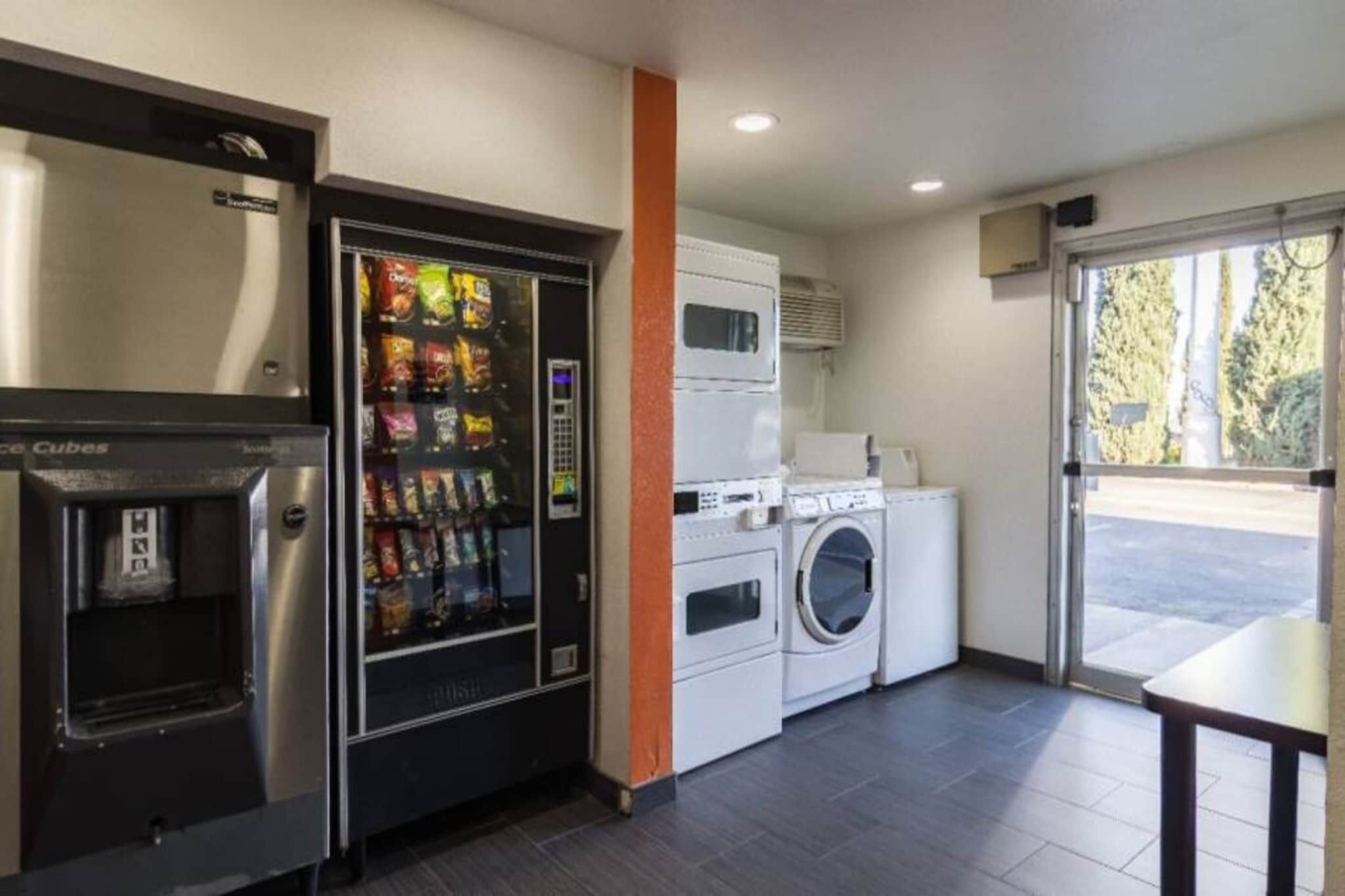 Una kitchenette con una máquina expendedora, una lavadora y un microondas.