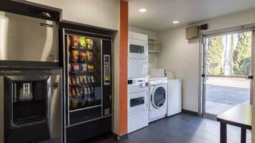 Una kitchenette con una máquina expendedora, una lavadora y un microondas.