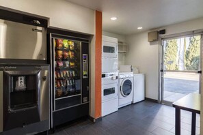 A kitchenette with a vending machine, a washing machine, and a microwave.