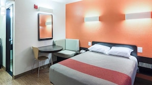 Een hotelkamer met een bed, een bureau, een stoel en een spiegel.