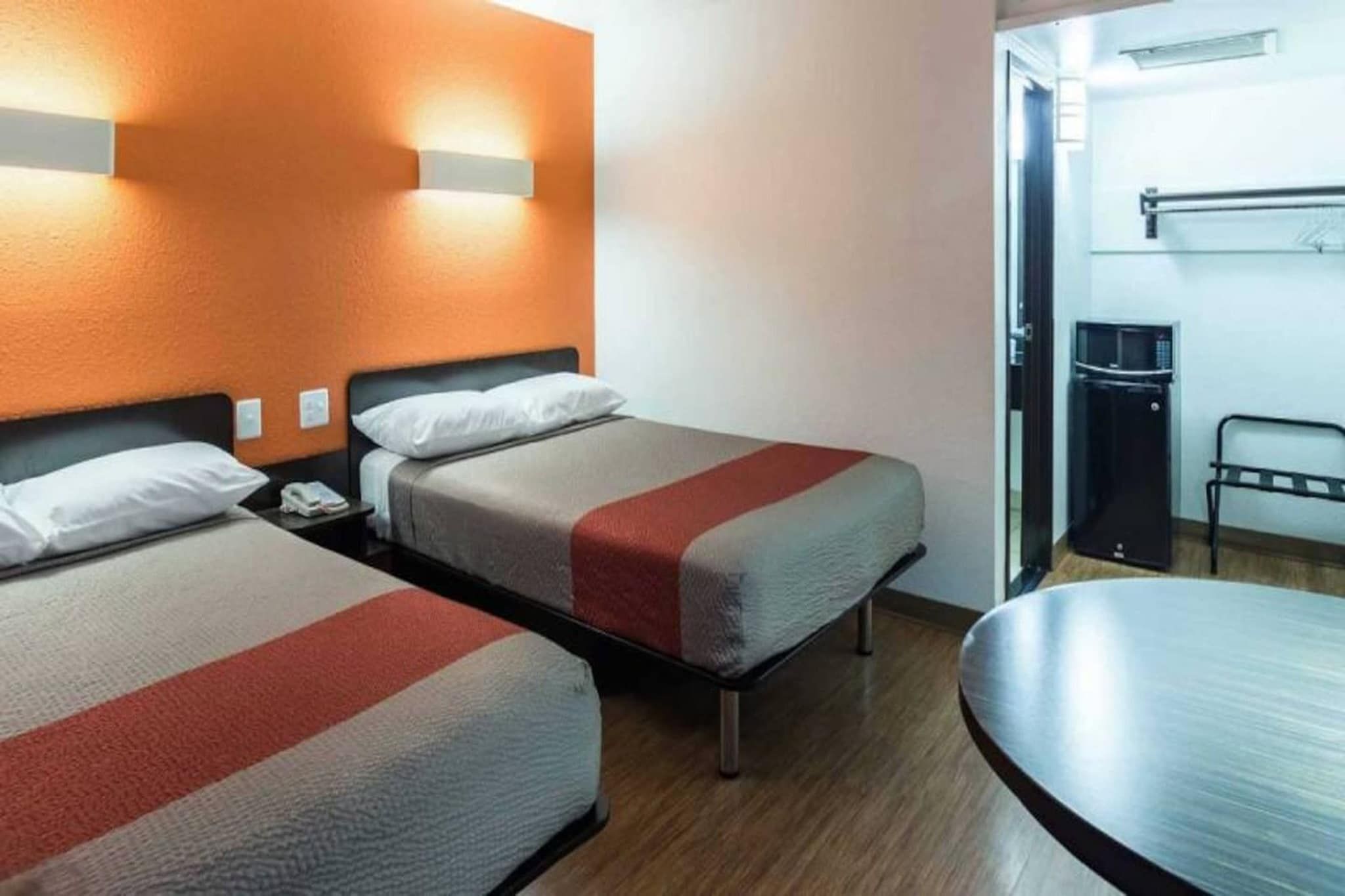 Habitación de hotel con dos camas, un escritorio, una silla y un microondas.